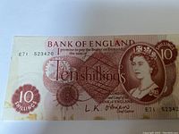 Front side of UK Ten Shillings banknote showing Queen Elizabeth II portrait, denomination and Bank of England text.