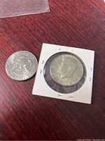 1969 Kennedy half dollar coin in holder and 1999 loose coin showing obverse sides with Kennedy profile