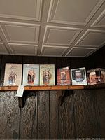 Six Budweiser Discover America Series steins and mugs in original boxed packaging displayed on a wooden shelf under ceiling tiles.