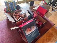 Boxed string lights holiday gift boxes and contents in open boxes on a table, showing multiple wrapped light-up gift boxes with bows and pine cones.