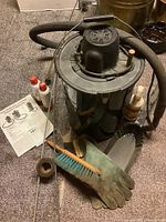 Full view of fireplace vacuum, hose, brushes, gloves, and instruction sheets on carpeted floor.