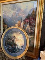 Two framed puzzles, one rectangular featuring a church scene and one circular featuring a lighthouse.