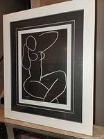 Front view of white wood framed black and white print of a seated nude figure sketch by Matisse