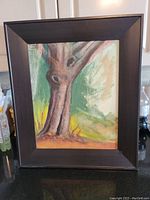 Full view of the framed original oil painting showing the tree with a thick trunk and surrounding foliage in green, yellow, and beige tones.