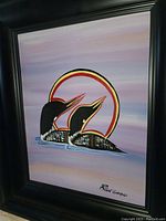 Frontal view of the framed painting showing two loons with a stylized red-yellow halo on a purple gradient background