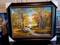 Painting in decorative black and gold frame with protective corner covers.