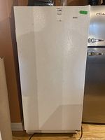 Front view of white Kenmore standing freezer with visible surface scuffs and textured door.