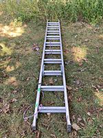 Full view of the 10-foot aluminum extension ladder lying on grass, showing overall length and aluminum construction.