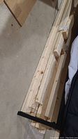 Stack of used 2x4 lumber pieces laid out on a basement floor showing lengths and wood grain
