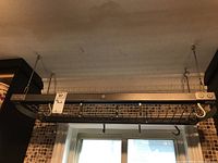 Frontal view of suspended pot rack showing full grid shelf and hanging hooks