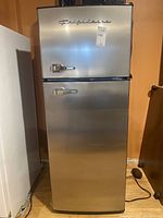 Front view of stainless steel refrigerator showing doors, handles, and seller sticker