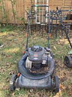 Front view of Remington push lawnmower showing the engine, wheels, and handles with signs of wear and dirt.