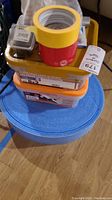 View showing three boxes: two plastic screw boxes and piles of tape rolls on top placed on a foam roll.