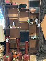 Front view of a tall faux wood shelving unit with multiple sections and compartments, various items placed on some shelves.