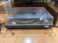 Front view of the Toshiba SR-250 turntable showing the dust cover, platter, control buttons, and power cord.