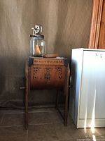 Bentwood butter churn with metal crank, decorative painting, measuring approx. 25x15x30.5 inches, next to a modernish filing cabinet for scale.