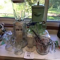 Photo showing Osterizer blender with glass pitcher, various glass parfait cups, glass measuring cup, and metal canister.