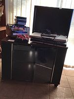 Wide view of entertainment lot including TV, DVD player, media stacks, remote toy, and entertainment unit