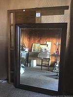 Wood framed mirror measuring 36x50 inches, dark wood frame with some wear, no hanging hardware visible