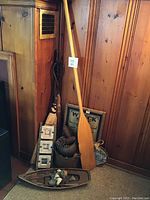 View showing wooden paddle, brooms, photo frames, metal buckets, and wood signs arranged against wood paneling