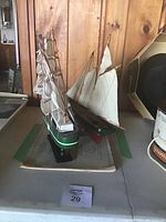 Two wooden model ships with multiple masts and sails painted green with white and red stripes, placed on 1974 navigational charts.