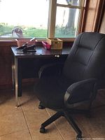 Fabric black office chair and wooden desk by window