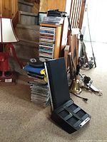 Photo showing Samsung DVD player, Netgear router, wooden CD stand with multiple CDs stacked, along with CD carrying cases and miscellaneous items