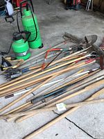 Overview of yard tools and two green garden sprayers