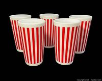 Five white milk glass tumblers with vertical red stripes, arranged on black background to show full design and shape.