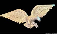 Full front view of large cast metal eagle with wings spread horizontally, showing detailed feather work and slightly aged patina.