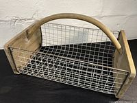 Front angled view showing wooden handle and wire mesh sides, illustrating size and construction