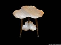 Full view of the two-tiered clover-shaped oak side table on black background showing shape and legs.