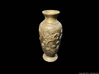 High contrast image showing front view of the vintage brass or bronze Asian vase with crane and cherry blossom relief motif against black background.