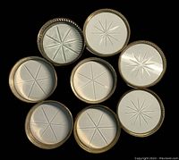 Top view of 8 vintage glass coasters with varied sterling silver rims and starburst or linear cut glass designs.