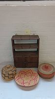 Bamboo/rattan wall shelf displayed behind three woven baskets with various patterns and colors.