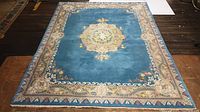 Full view of rug on floor showing field, medallion and border