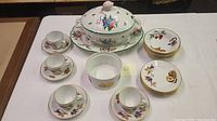 Full view of all chinaware items on table, showing tureen, cups and saucers, plates