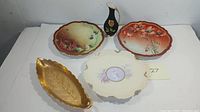 Top view of four assorted porcelain items with floral motifs and gilt embellishments