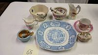 Overview of 9 assorted porcelain items including transferware plate, cups, pitchers, a mortar and pestle, and trinket dish