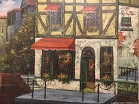 Close-up of the oil painting depicting the European-style building facade with half-timbered construction, red awnings, flowers, and street details.