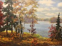 Close-up photo showing detailed brushwork and color composition of lakeside autumn scene with trees and water under cloudy sky.