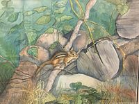 Close-up of watercolor painting showing chipmunk on branch with leaves, rocks, and grass in natural scenery.