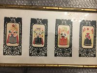 Front view of framed papercut art showing four colorful Peking Opera singer faces with intricate black borders.