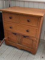 Front angled view showing overall shape, wood grain, knob details and base scallop