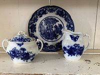 Complete set showing plate, cream pitcher, and covered sugar bowl with blue flow blue transfer patterns.