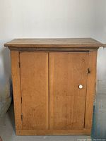 Front view of antique pine jam cupboard showing two closed doors, ceramic knob on the right door, and rustic finish.