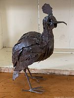 Front angle of rusted metal salvage bird sculpture with visible textured metal plates and detailed head.