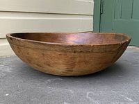 Side profile view of the hand-carved wooden bowl on a concrete step.