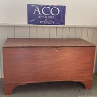 Front view of large antique 19th century wooden blanket chest painted red with minor wear.