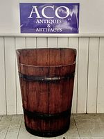 Front view of large vintage Portuguese grape picking barrel with heart-shaped top and three black metal hoops.